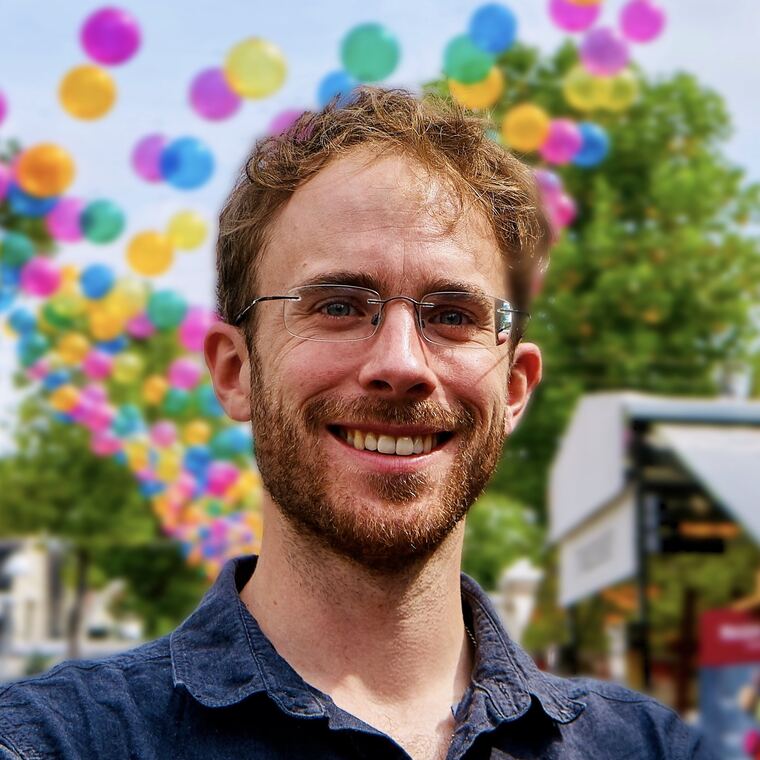 Matthijs Zwinderman, lachend, met kleurige ballonnen op de achtergrond